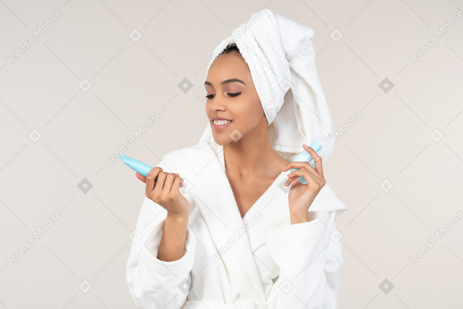 Mujer negra con bata blanca y toalla para la cabeza disfrutando de su rutina de cuidado de la piel
