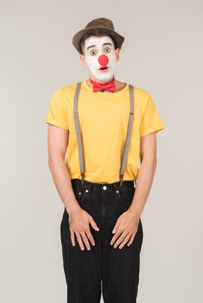 Surprised male clown standing with hands on elongated