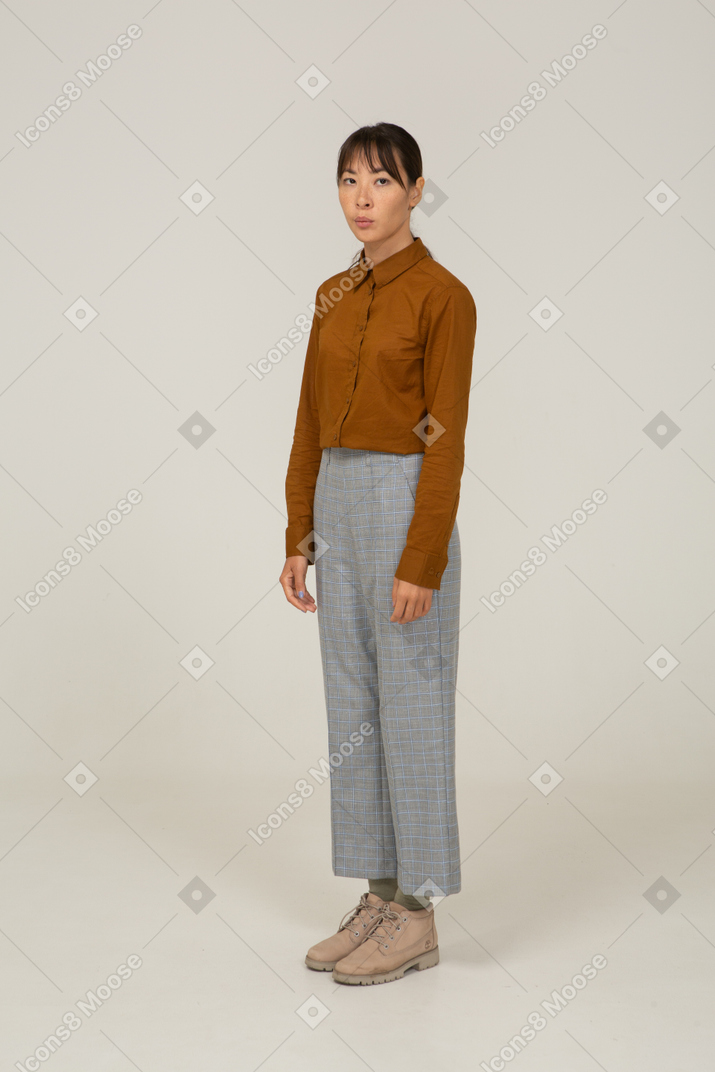 Three-quarter view of a young asian female in breeches and blouse looking at camera