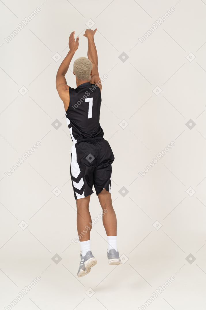 Three-quarter back view of a young male basketball player throwing something
