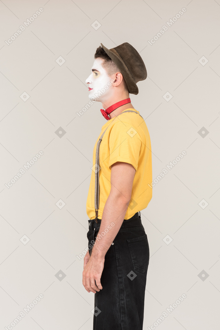 Serious looking male clown standing in profile