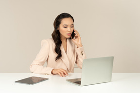 아시아 여성 회사원 전화 통화 및 노트북에서 작업