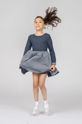 Vista frontal de una niña sonriendo a mitad de un salto