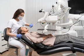 Longitud total de una dentista examinando a su paciente acostada en un gabinete de hospital