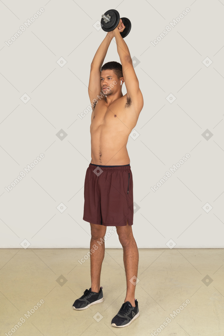 Vue de trois quarts d'un jeune homme athlétique tenant un haltère