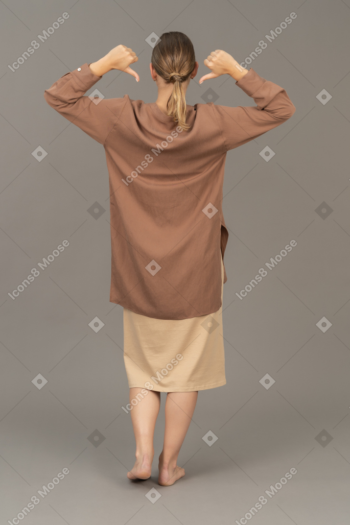 Lato posteriore di una donna con i pollici in giù che puntano alla sua schiena