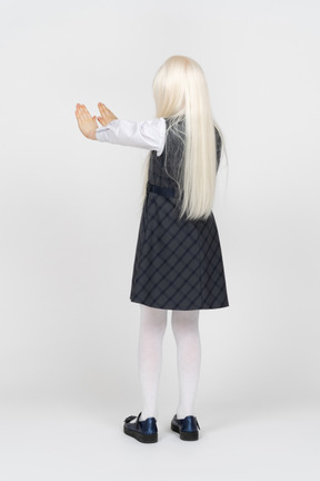 Back view of a school girl with her hands up