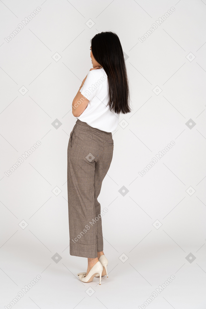 Three-quarter back view of a young lady in breeches and t-shirt touching chest
