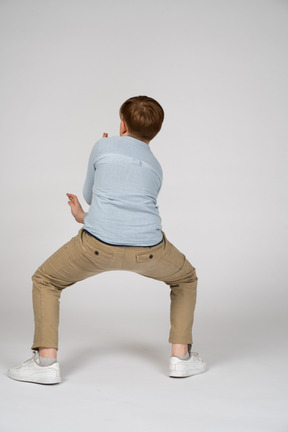 A boy in a blue shirt is doing a yoga pose