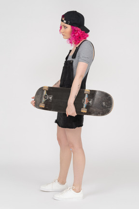 Hunchbacked teenage girl holding a skateboard in profile