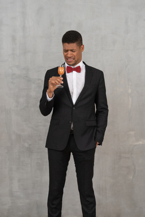 Jeune homme avec un visage froissé regardant un verre de champagne