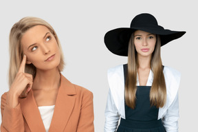 Thoughtful business woman standing next to young woman in black hat