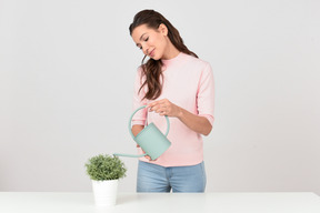 Привлекательная молодая женщина поливает комнатное растение