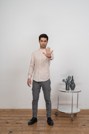 Vista frontal de um homem com roupas casuais mostrando um gesto de pare