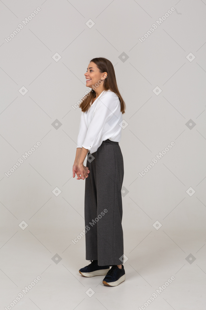 Vista di tre quarti di una giovane donna sorridente in abiti da ufficio che si tiene per mano insieme