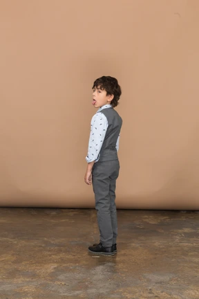 Side view of a boy in grey suit showing tongue