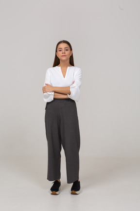 Vista frontal de uma jovem pensativa em roupas de escritório, cruzando os braços
