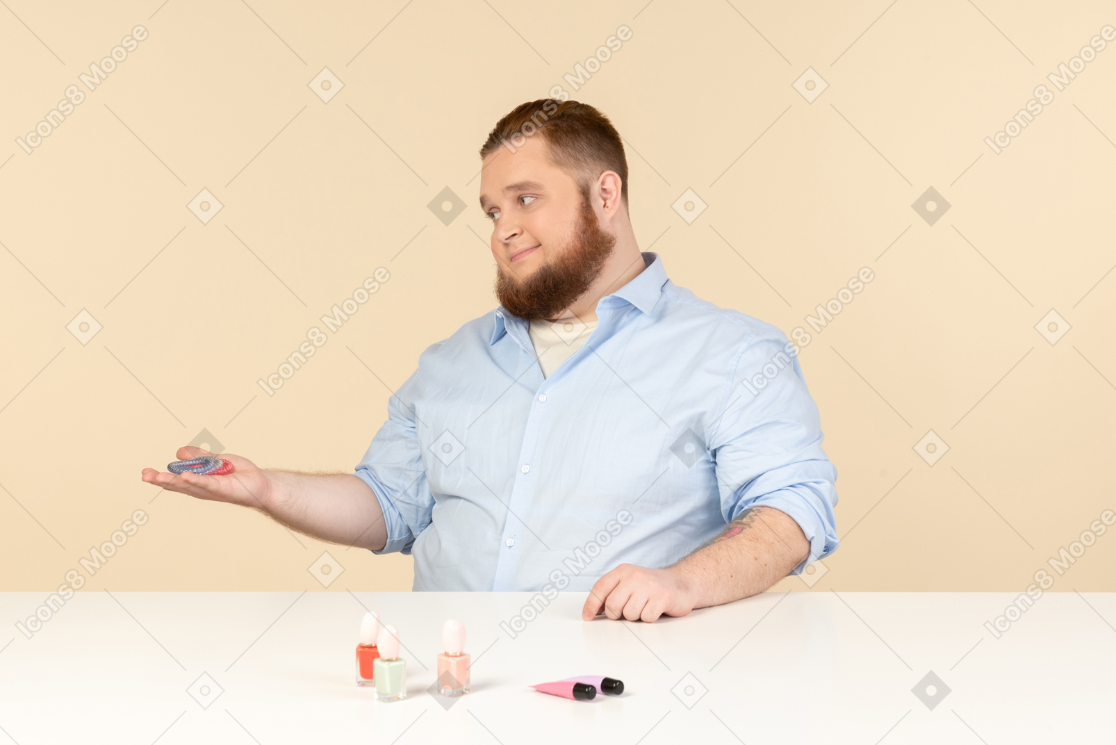 Big man sitting at the table and showing nail polishes