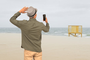 Man standing on the beach and filming the sea