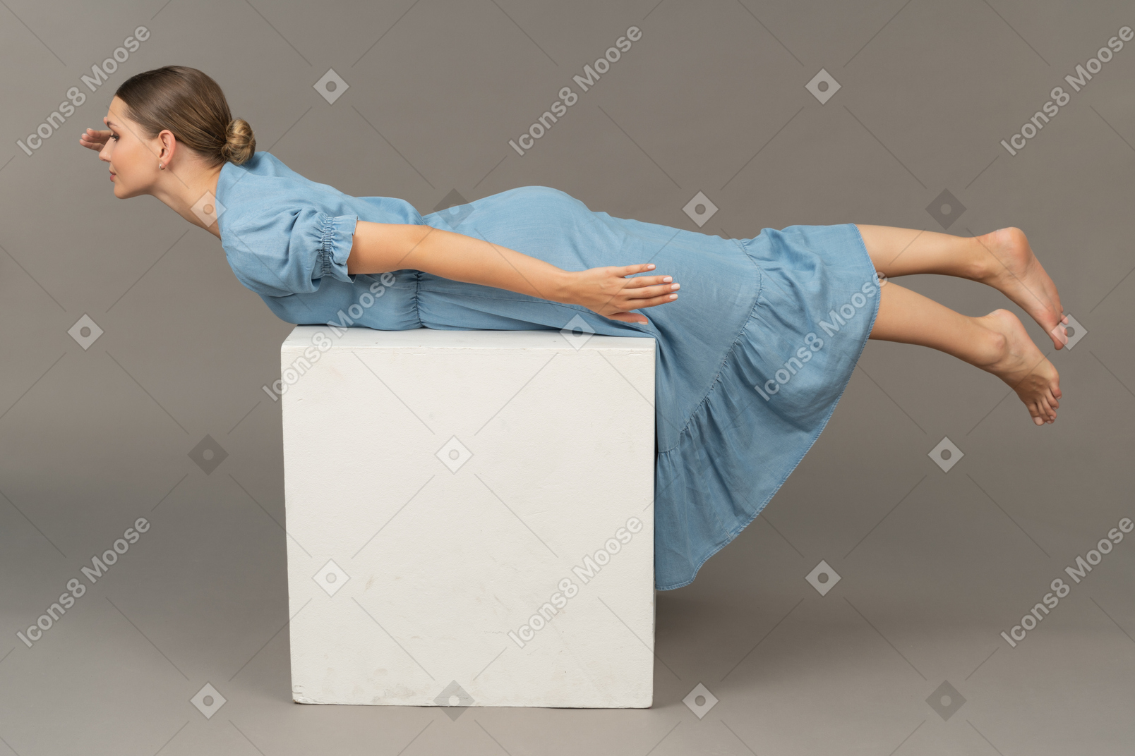 Вид сбоку на молодую женщину, лежащую на кубе