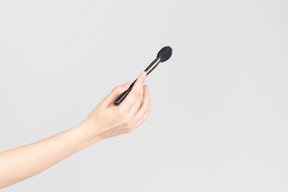 Female hand holding face makeup brush