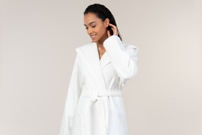 Black woman in white bathrobe going about her morning routine