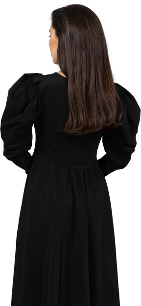 后面的观点的一位年轻的女士穿着一件黑色的连衣裙，手牵着手