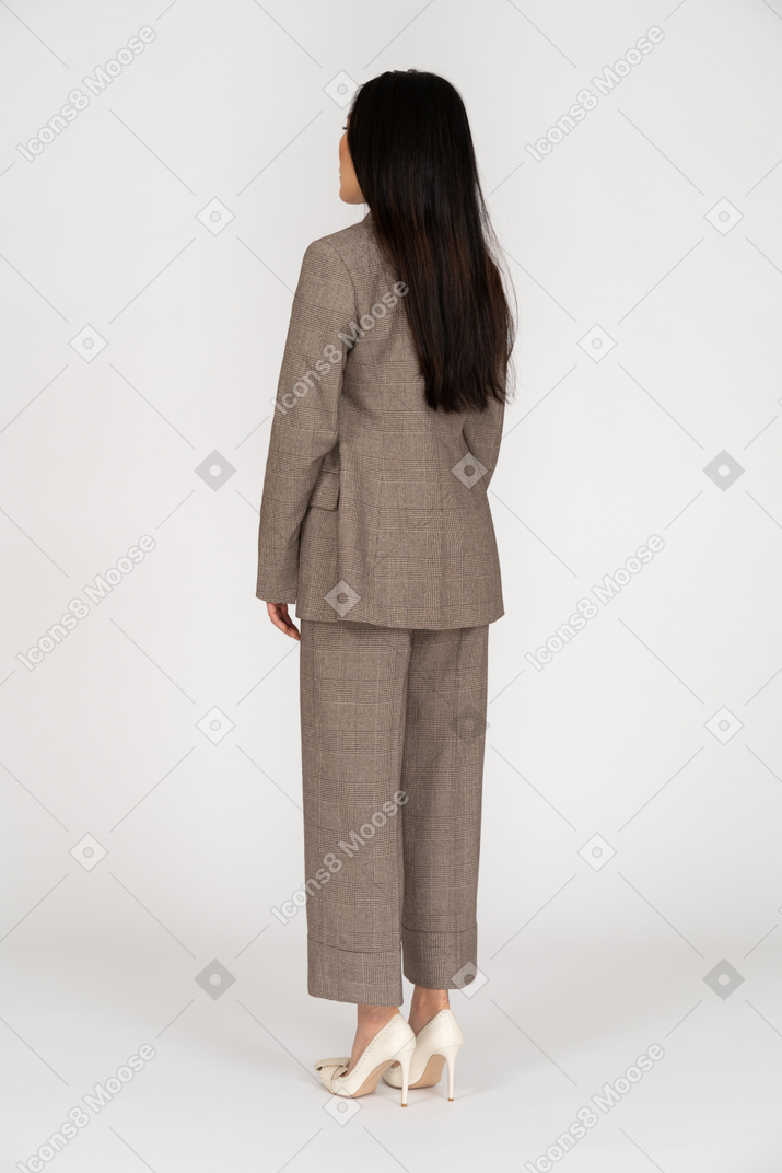 Three-quarter back view of a young lady in brown business suit