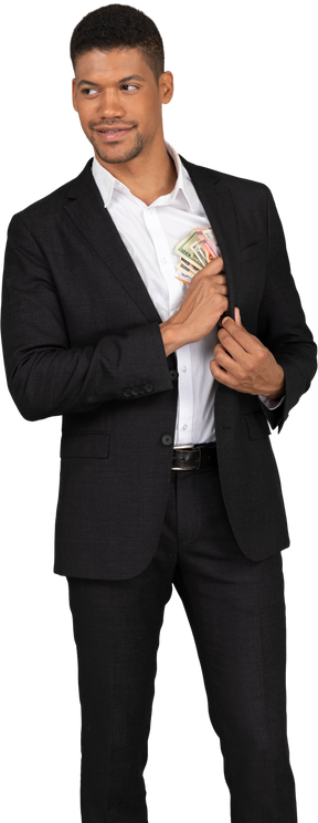 Vista frontale di un giovane in abito nero che mette le banconote in tasca