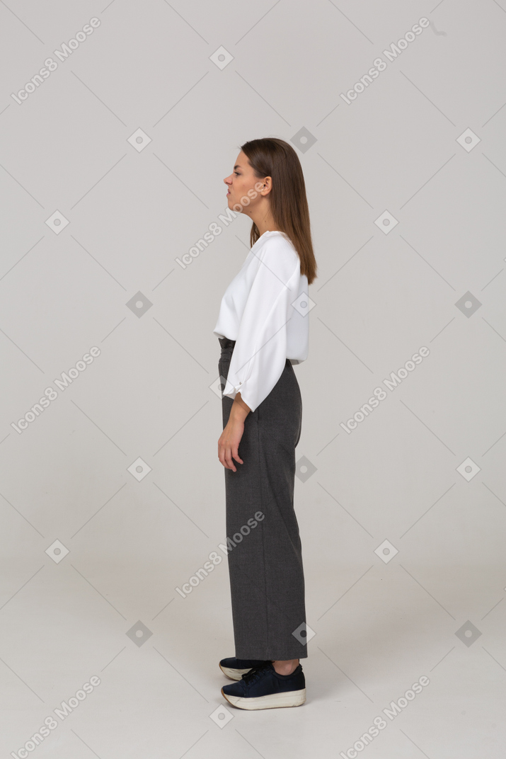 Vista lateral de uma jovem descontente com roupas de escritório, olhando para o lado
