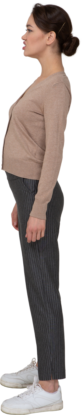 Vista posterior de tres cuartos de una dama disgustada en jersey y pantalones mirando a un lado