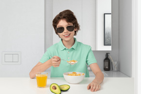 Boy in sunglasses eating breakfast