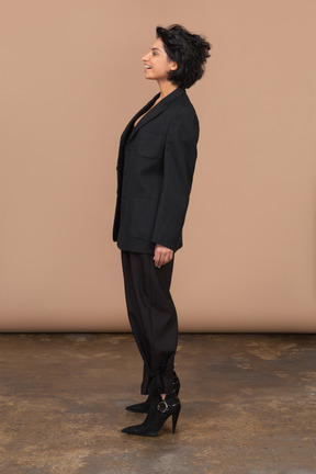 Vue latérale d'une femme d'affaires souriante surprise portant un costume noir