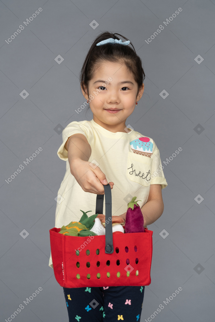 Porträt eines kleinen mädchens, das einen einkaufskorb hält