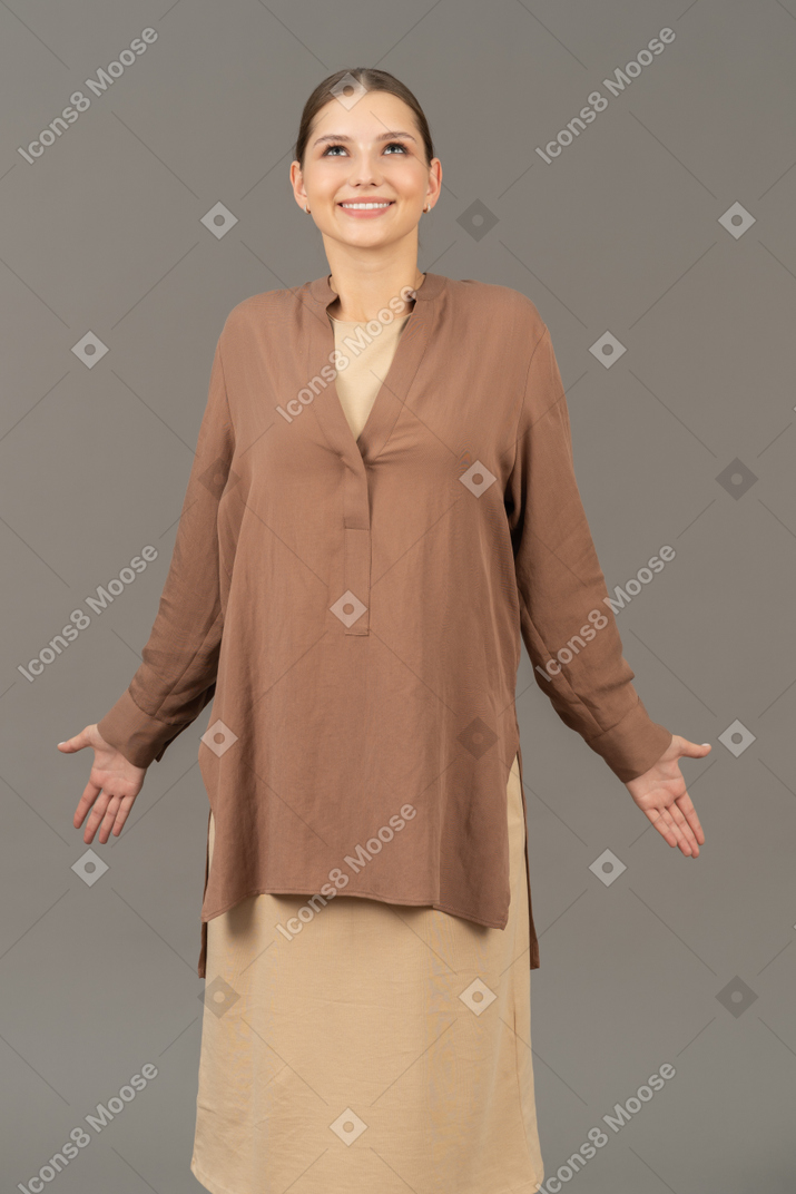 Front view of smiling young woman looking up with open arms