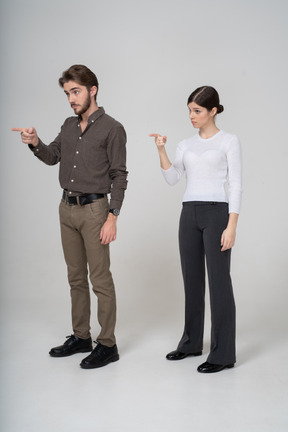 Three-quarter view of a young couple in office clothing pointing finger forward