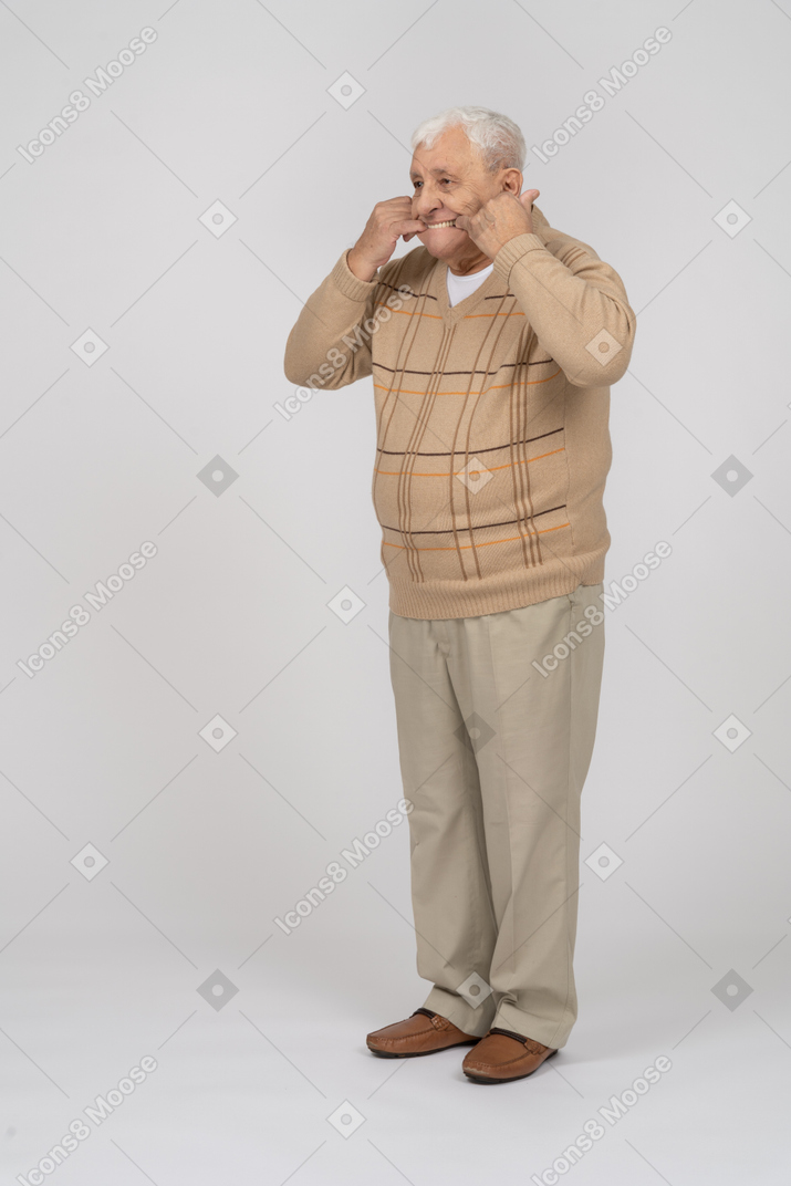 一位穿着休闲服的老人把手指放在嘴里的正面图