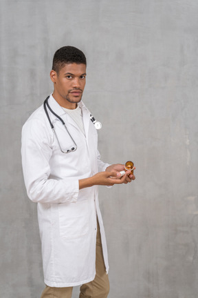 Médico varón sosteniendo un frasco de pastillas
