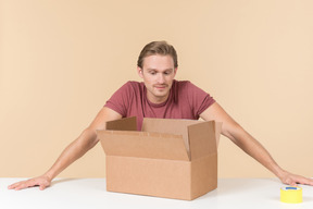 Sad looking young guy sitting in front of open box