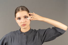 Front view of a young woman in a jumpsuit removing make-up