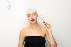 Young woman looking through magnifying glass