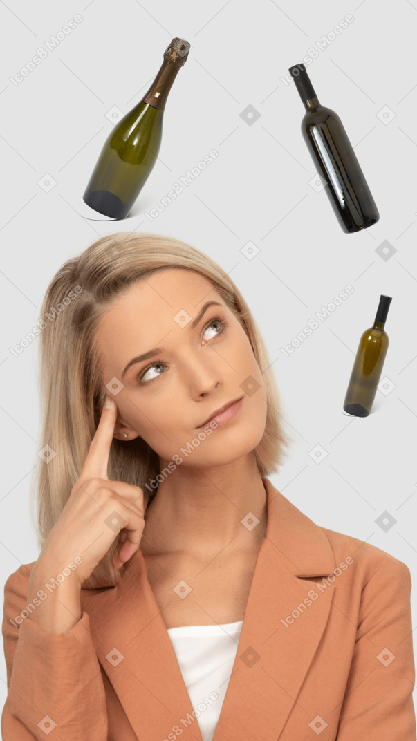 A woman is looking up at bottles above her head