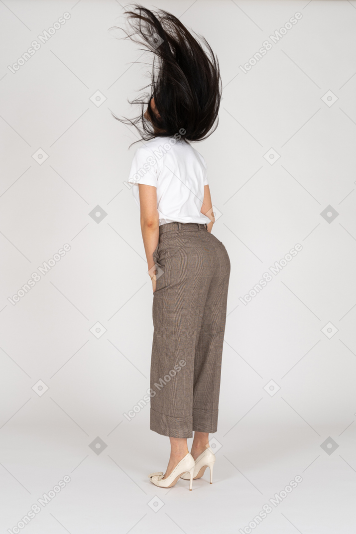 一位年轻的女士，穿着马裤和凌乱的头发的t恤的四分之三后视图
