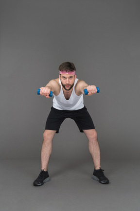 Homem esportivo fazendo exercícios para os braços usando halteres azuis