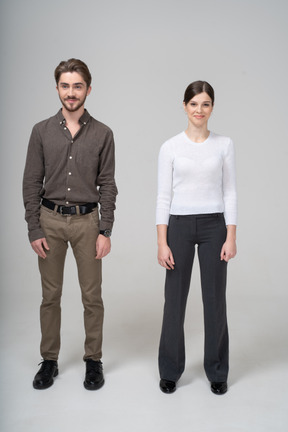 Vista frontal de um jovem casal satisfeito com roupas de escritório