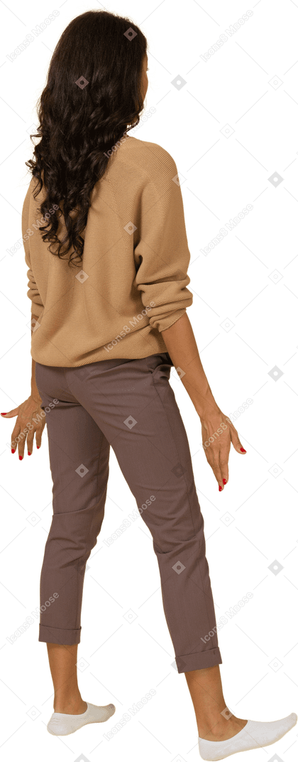 Vista posterior de tres cuartos de una mujer joven de piel oscura que cuestiona extendiendo sus manos