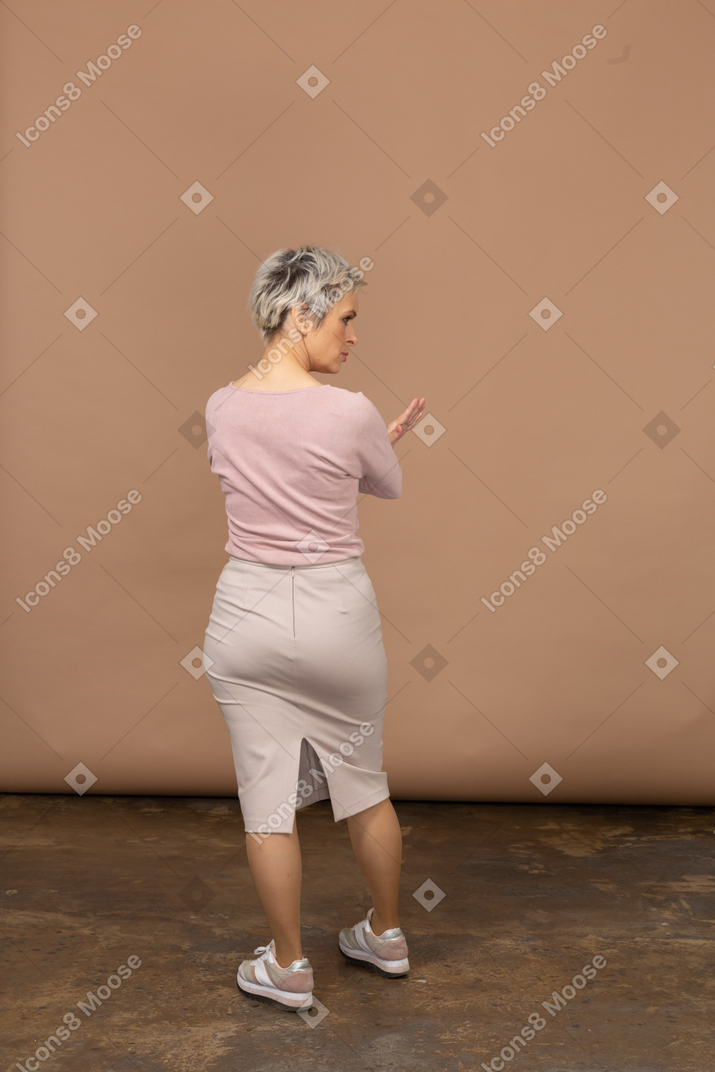 Retrovisor de uma mulher com roupas casuais mostrando um gesto de pare