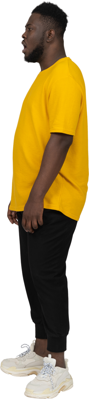 Side view of a shocked young dark-skinned man in yellow t-shirt