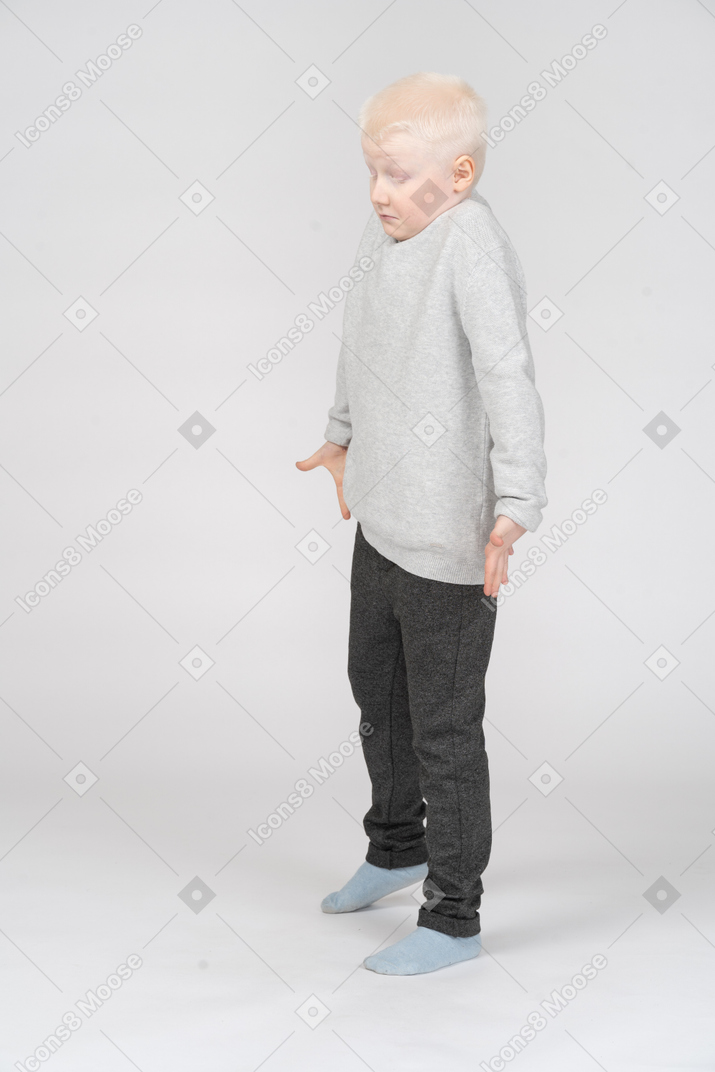 Vista de tres cuartos de un niño pequeño encogiéndose de hombros