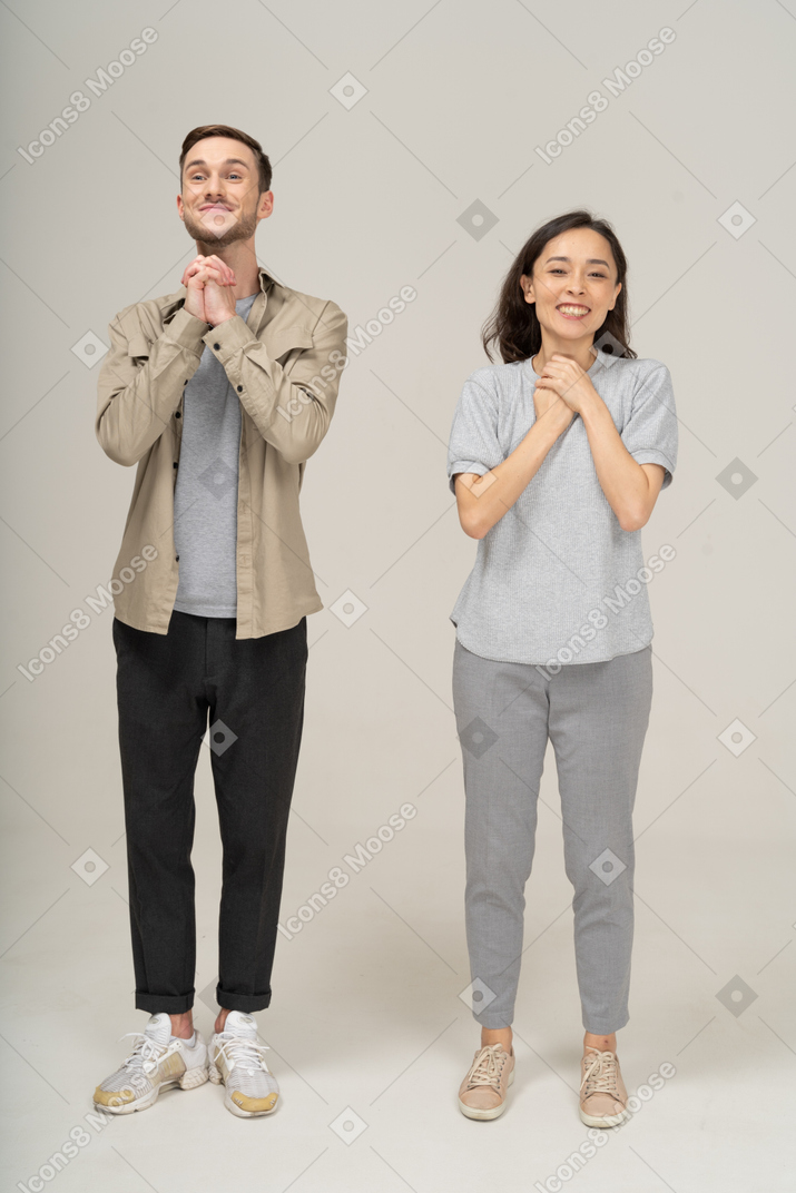 Cheerful young couple smiling with hands on chest